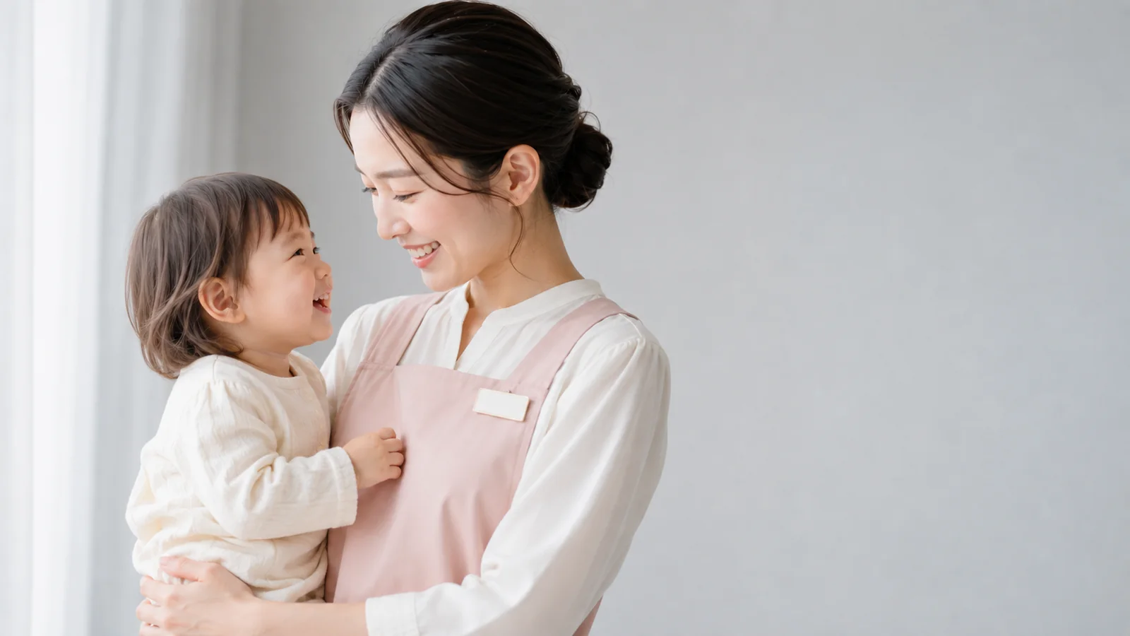 お子様を抱きかかえて笑いあう保育士